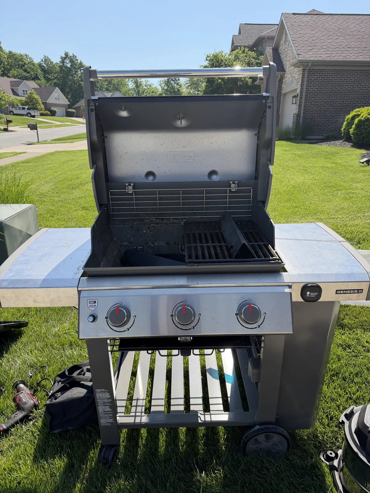 Before: Weber Genesis II 3-burner gas grill mid-service in a West Chester backyard — grates removed, heat shields and burner area exposed with carbonized buildup